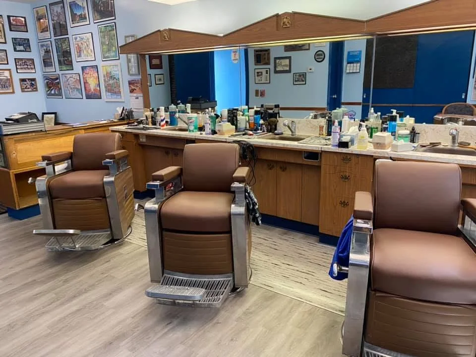 Three brown leather barber chairs facing the mirror and the counter
