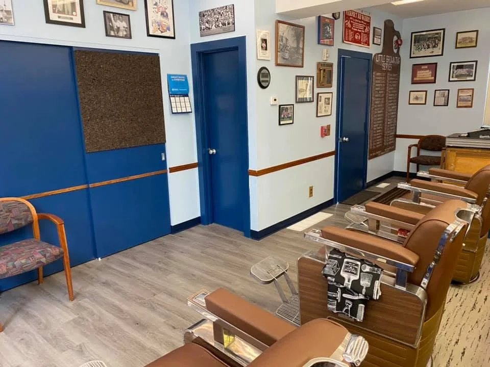 The shop: barber chairs along one wall, blue doors and framed pictures